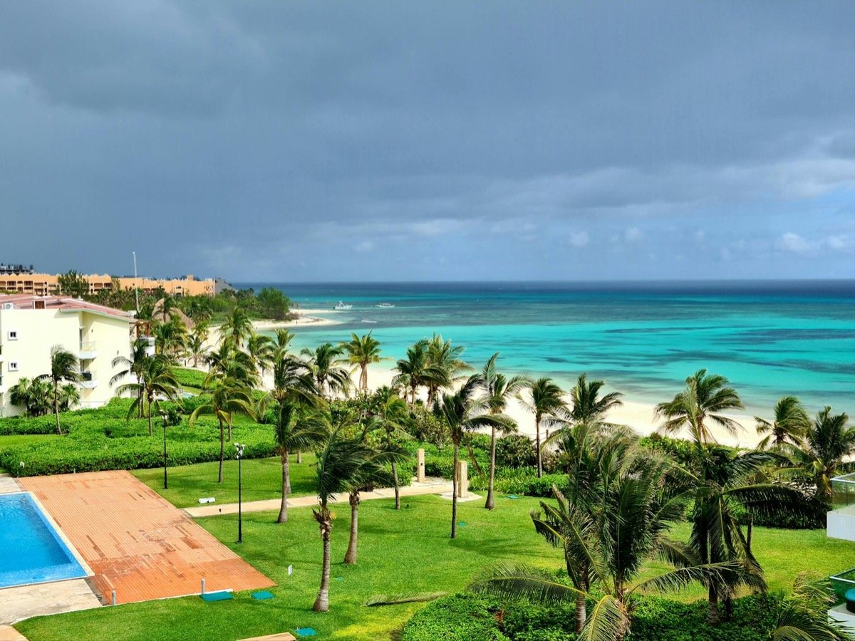 Piscina de resort de lujo con vistas al turquesa del Mar Caribe, palmeras y playa de arena blanca
