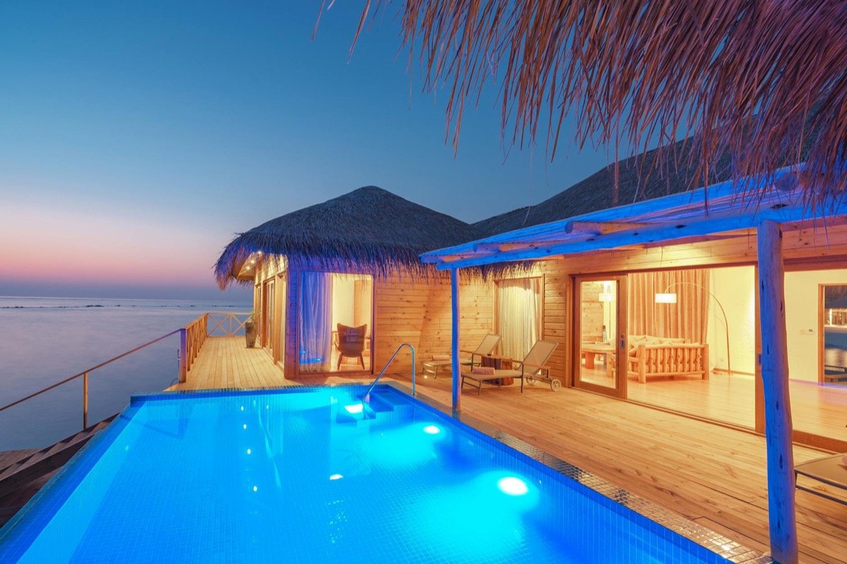 Luxury overwater bungalow with private infinity pool at sunset over a tropical ocean