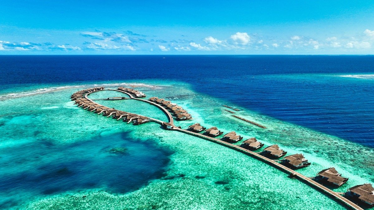 Aerial view of a luxury resort in the Maldives with overwater villas and turquoise lagoon