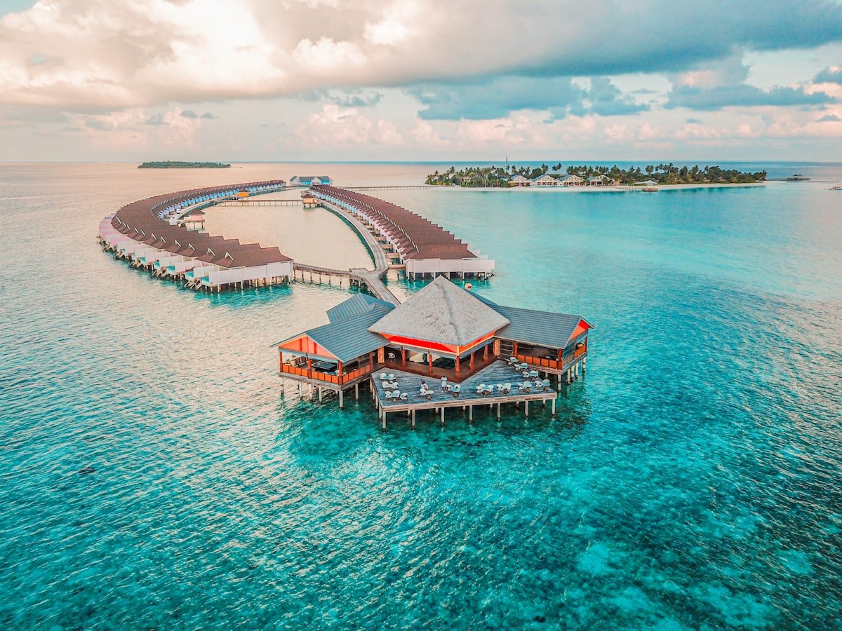 Aerial view of overwater villas and walkways extending over turquoise Maldives lagoon
