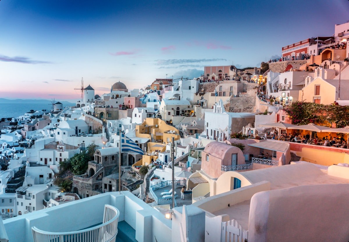 Whitewashed buildings and windmill in Oia village, Santorini, at sunset with pink sky