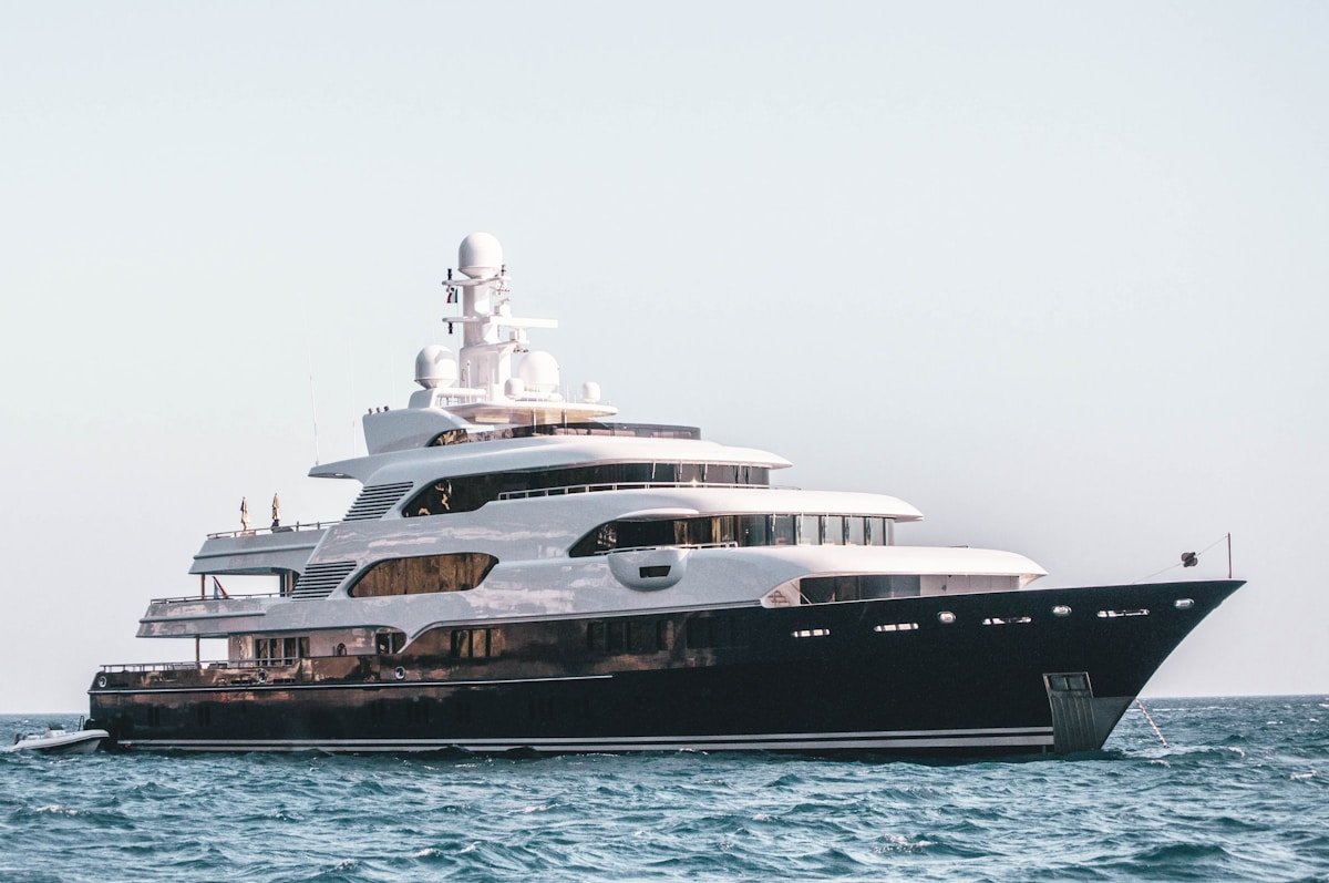 Large superyacht with dark hull anchored in open Mediterranean waters