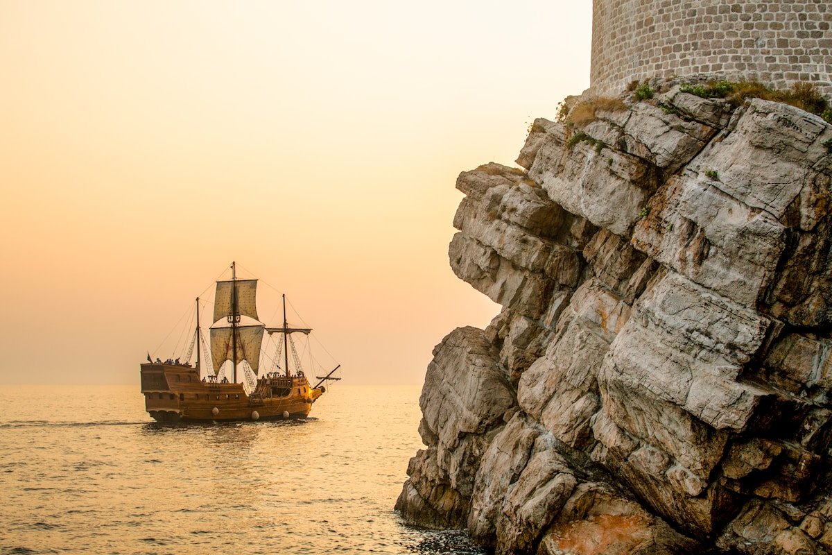 Traditional sailing vessel near the ancient stone walls of Dubrovnik, Croatia at sunset